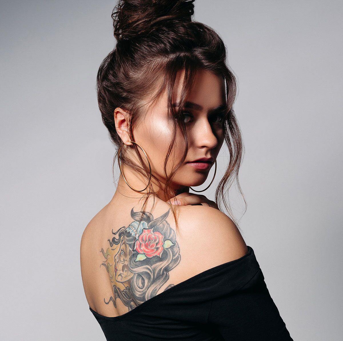 A woman looking back with a large tattoo on her back.