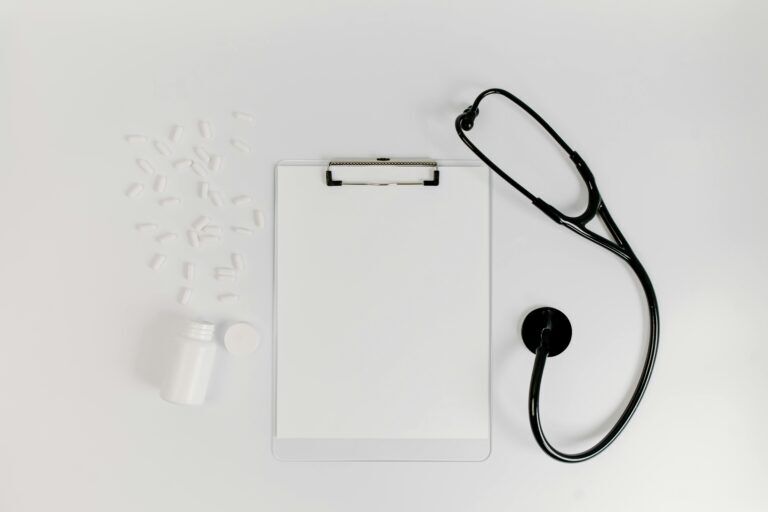 A bottle of spilled pills next to a clipboard and a stethoscope